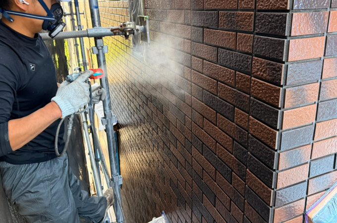 凹凸の深いタイルにクリヤー塗料をエアレスで吹き付けている様子｜深目地タイルへの均一なクリヤー塗装作業