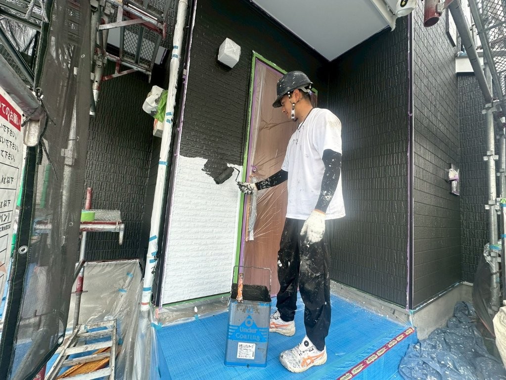 T様邸 ブラック系外壁の中塗り塗装をローラーで施工中